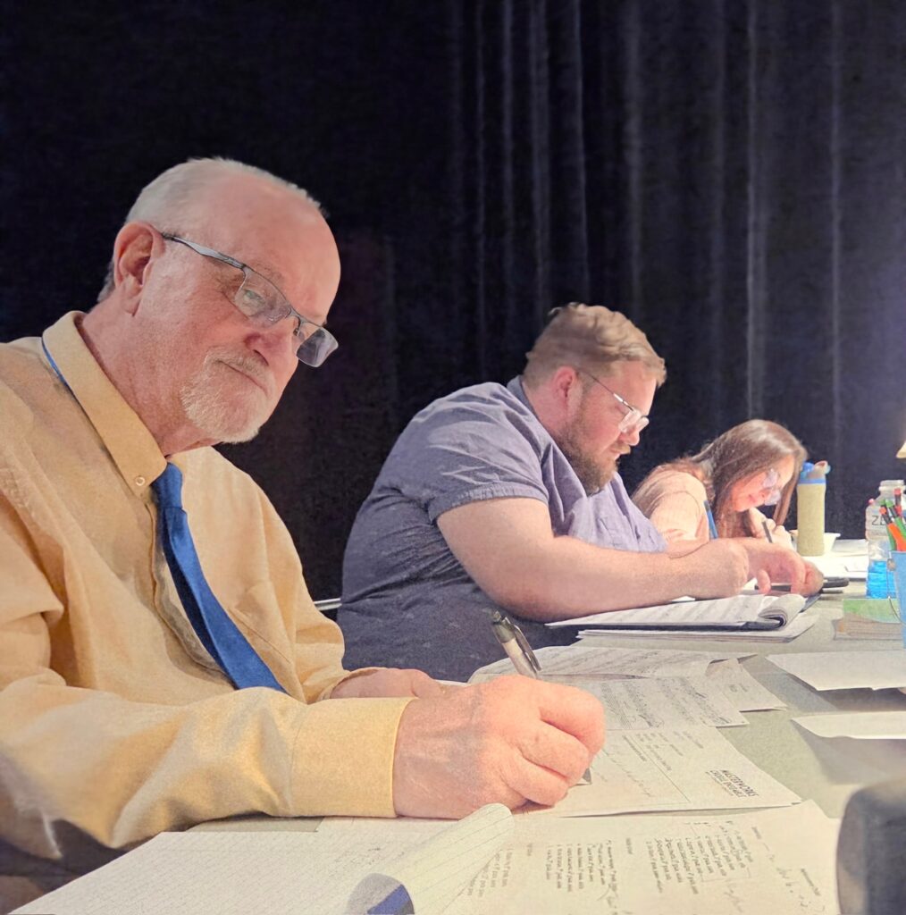Gary Witley, Austin Schlichting, and Jennifer Hermann review notes during the 2025 Youth Music Competition hosted by Masterworks Choral Ensemble.